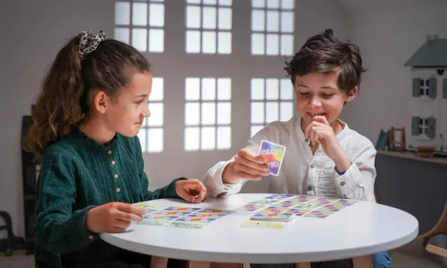 Deux enfants jouent à un jeu de cartes coloré, une belle illustration d'activités sans écran pour adultes et enfants.