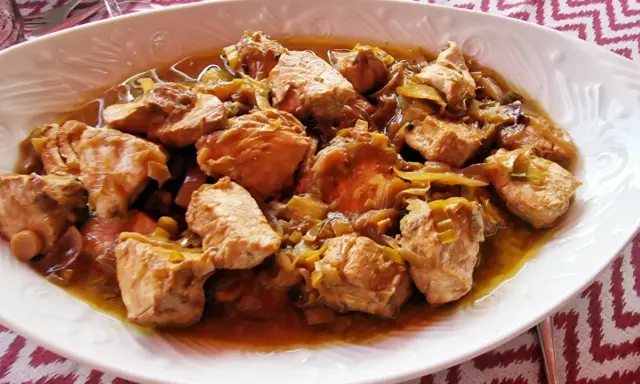 Sabroso bonito en escabeche, trozos de pescado tierno con cebolla en una salsa dorada.