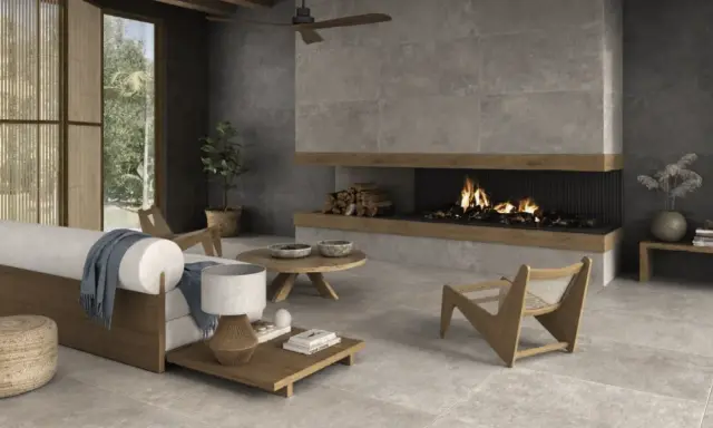Salón moderno con chimenea encendida, sofá blanco y suelo de cemento pulido.