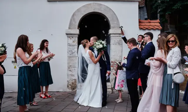 Para młoda całuje się przed kościołem, goście sypią bańki mydlane. To piękny ślub jednostronny, przysięga miłości.