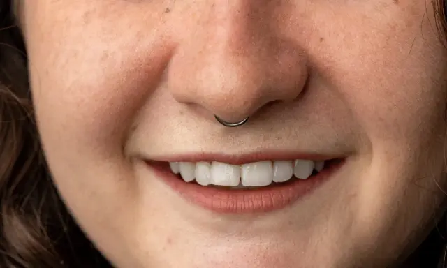 Uśmiechnięta twarz z kolczykiem w nosie (septum).
