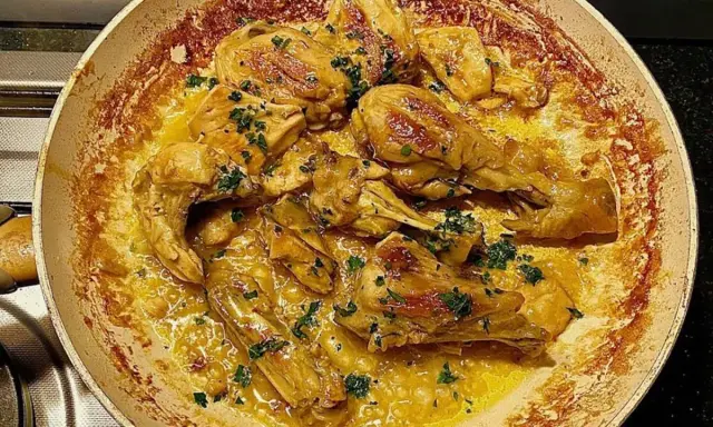 Succulento pollo alla marengo in padella, con erbe aromatiche fresche e una ricca salsa dorata.