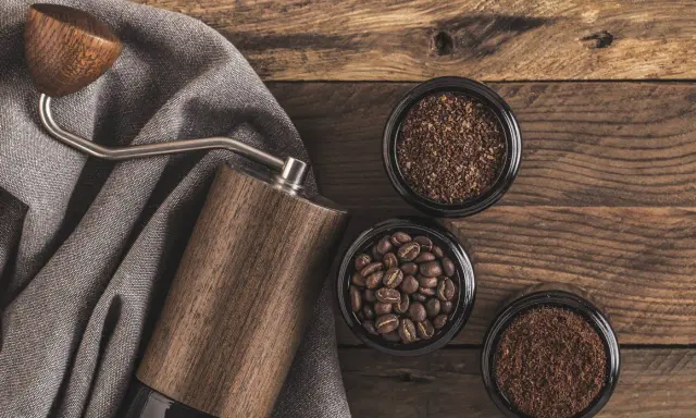 Holz-Kaffeemühle mit drei Behältern: ganze Bohnen, grob gemahlener und feiner, kleiner brauner Kaffee.