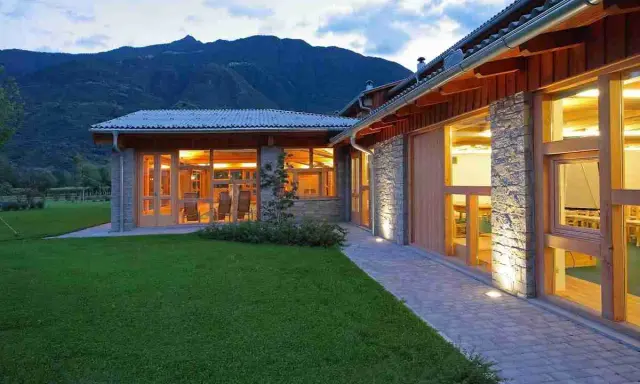 Agriturismi con fattoria immersi nel verde, con architettura in pietra e legno, illuminati al tramonto.