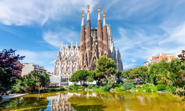 La Sagrada Familia, con le sue torri svettanti e il riflesso sull'acqua, sembra un sogno che attende il suo completamento. Chissà quando finirà la Sagrada Familia.