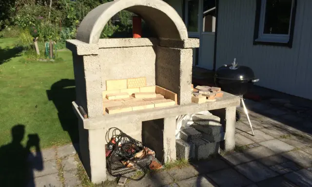 Bygga grill av tegelstenar. En nybyggd betonggrill med tegelstenar i eldstaden, redo för sommarens grillfester.