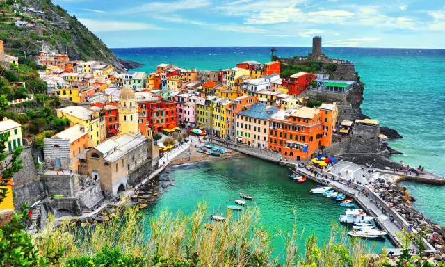 Vernazza, una delle Cinque Terre, con case colorate a picco sul mare turchese e un porticciolo pieno di barche.