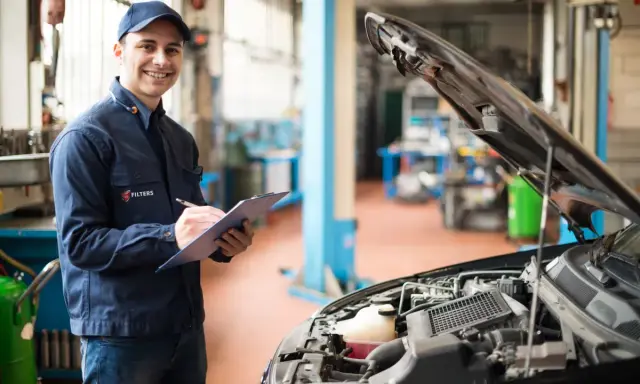 Uśmiechnięty mechanik notuje przebieg auta przed pierwszą wymianą oleju w silniku 1.5 TSI.