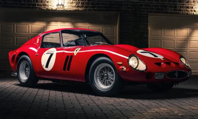 Roter Ferrari 250 GTO, das seltenste Auto der Welt, mit der Startnummer 7, steht vor einer Garage.