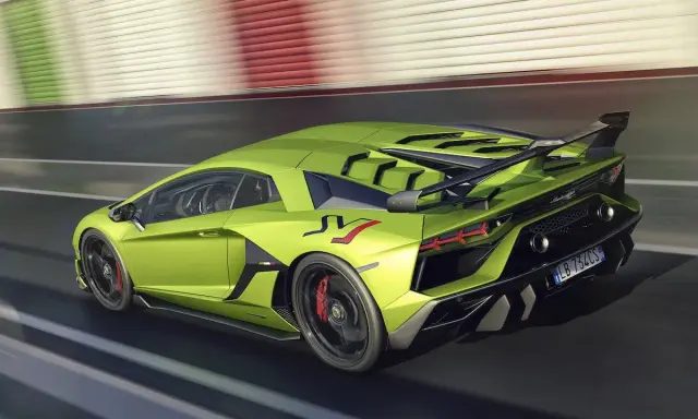 Un espectacular Lamborghini Aventador verde acelera en la pista, con su alerón trasero y detalles aerodinámicos en negro.
