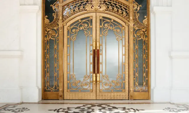 Prunkvolle goldene Doppeltür im **Art déco Baustil** mit filigranen Verzierungen und Marmorboden.