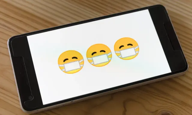 Trzy emoji w maseczkach na ekranie smartfona. Dowiedz się, jak usunąć wirusy z iPhone.