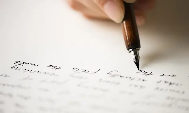Mano che scrive con una penna stilografica su carta, evocando il significato di un rapporto epistolare.