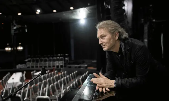 Tomas Ledin lutar sig mot en pianokant i en tom teatersalong, kanske förbereder han sig för Melodifestivalen.