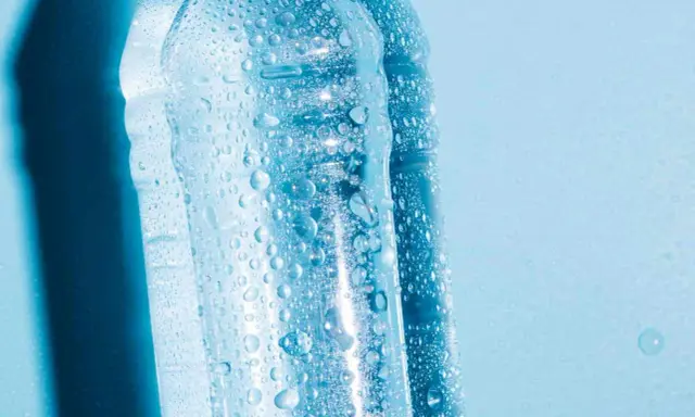Krople wody na plastikowych butelkach, sugerujące, czy można zamrozić wodę w butelce plastikowej.