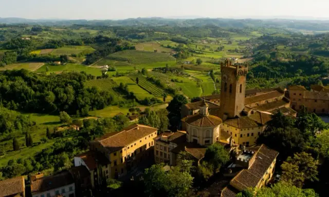 Un borgo medievale con una torre svetta tra le verdi colline pisane, un paesaggio da cartolina.