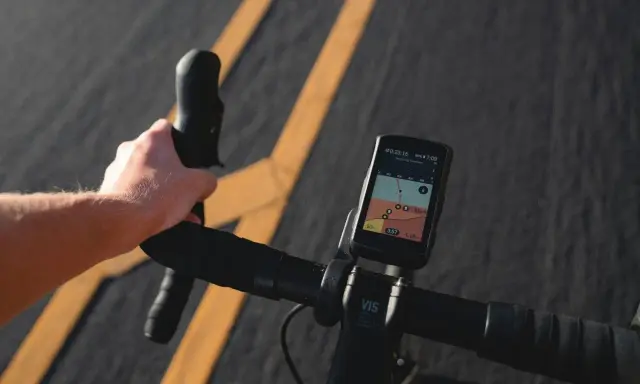 Rowerzysta trzyma kierownicę, na której zamontowana jest aplikacja na rower iPhone z mapą i danymi o trasie.