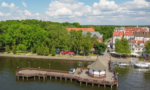 Malownicze Mazury: molo, urokliwe miasteczko i zielone drzewa. Idealne miejsce, gdzie najlepiej na Mazury.