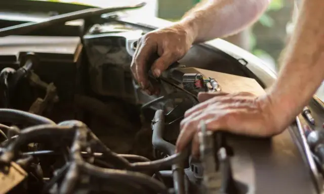Mecánico revisa el motor de un coche. El sonido de aire al acelerar el coche podría ser un problema.