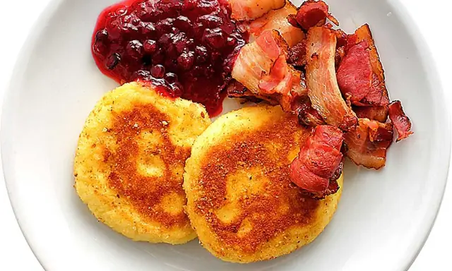 Två gyllene potatisbullar med lingonsylt och knaperstekt bacon. Ett klassiskt potatisbullar recept som passar till det mesta.