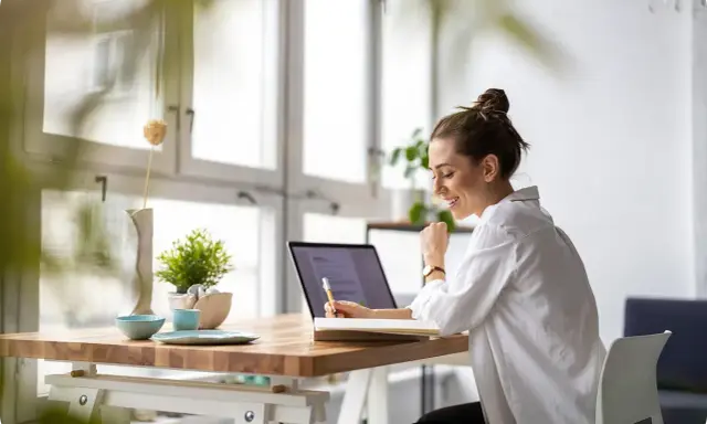 Uśmiechnięta kobieta pracuje przy laptopie, planując swój **ecommerce dropshipping**. Sukces w biznesie online!