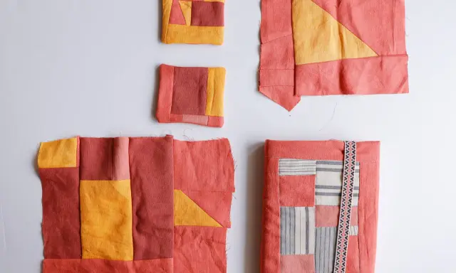 Kilka fragmentów tkanin w odcieniach koralu i żółci, tworzących wzory geometryczne. To jest właśnie patchwork – sztuka łączenia skrawków materiału.