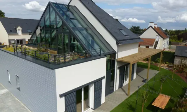 Maison moderne avec toit en verre spectaculaire, terrasse végétalisée et pergola en bois. Un rêve de maison ecc.