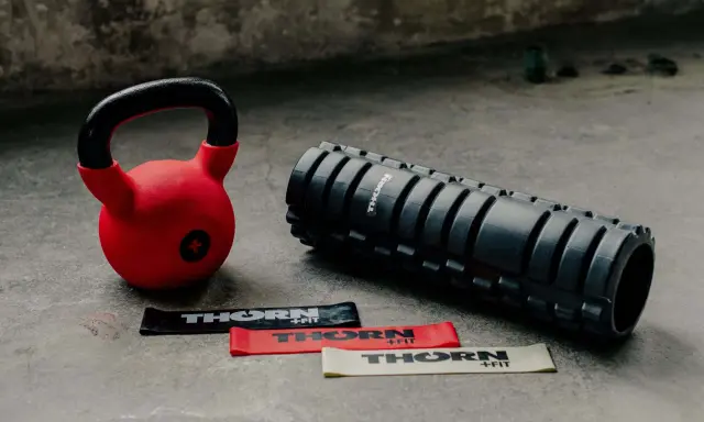 Czerwony kettlebell, wałek do masażu i taśmy oporowe. Idealny zestaw, by zacząć treningi z kettlebell.