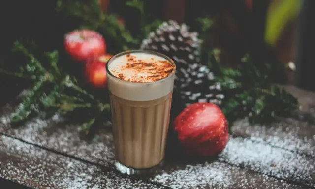 En krämig kaffedrink med kanel, omgiven av juliga äpplen och granris. Perfekt för mysiga stunder och inspirerar till egna kaffedrinkar recept.