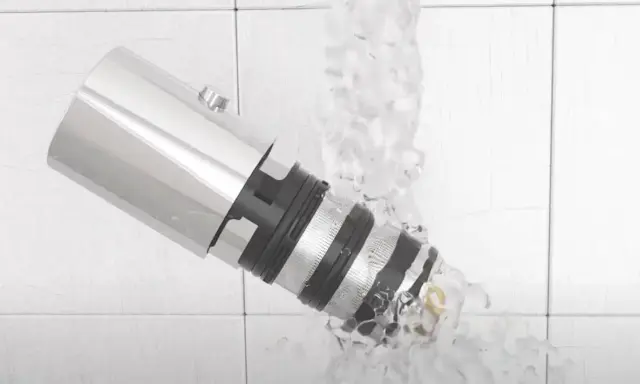 Detalle de un grifo termostático bajo un chorro de agua, mostrando su diseño y cómo limpiarlo.