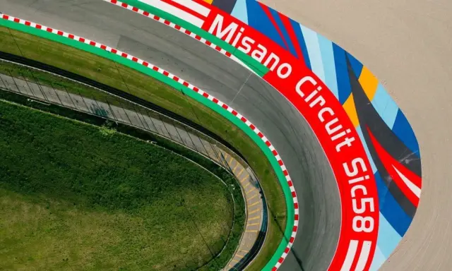 Vista aerea del circuito di Misano, con la scritta "Misano Circuit Sic58" in rosso e un disegno colorato.