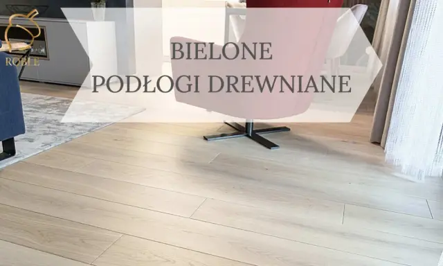 Jasne, bielone drewno na podłodze w salonie, z widocznym fragmentem granatowej kanapy i różowego fotela.
