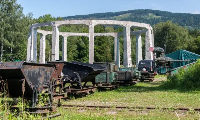 Ruiny budowli w muzeum molke, obok stare wagony kopalniane, ciężarówka i zielony namiot.