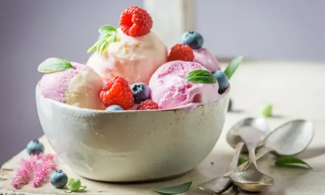 Deliciosos helados caseros de fresa y vainilla, adornados con frambuesas y arándanos frescos.