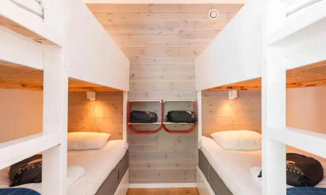 Två våningssängar i en mysig stuga, perfekt för camping i Åre. Sängkläder och sovsäckar redo för äventyr.