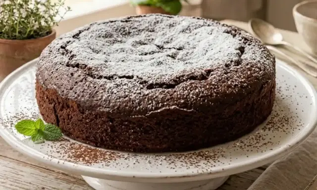 Torta all'acqua al cacao, soffice e golosa, spolverata di zucchero a velo e decorata con menta fresca.