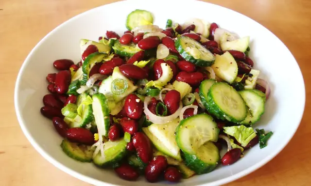 Salade colorée de haricots rouges, concombre, oignon rouge et céleri, prête à être dégustée.