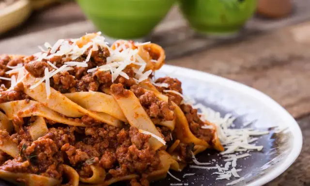 Pappardelle z bogatym sosem bolognese, idealne pytanie: jakie mięso do spaghetti? Posypane parmezanem.
