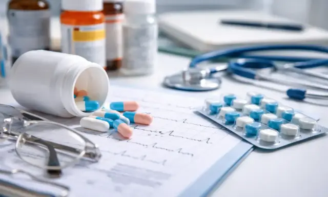 Kapsułki i tabletki, leki od psychiatry, leżą obok stetoskopu i okularów na dokumentach medycznych.