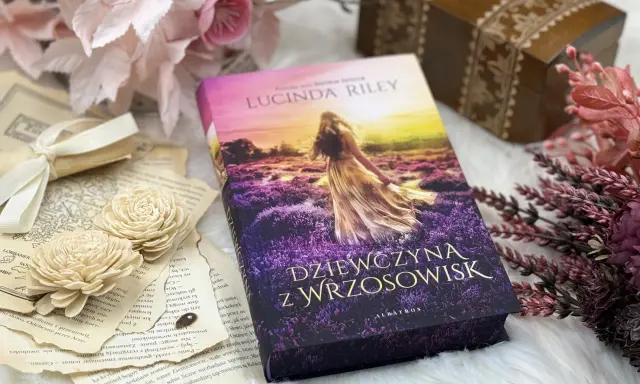 Dziewczyna z wrzosowisk, otoczona starymi księgami i kwiatami, zaprasza do świata pełnego tajemnic i przygód.
