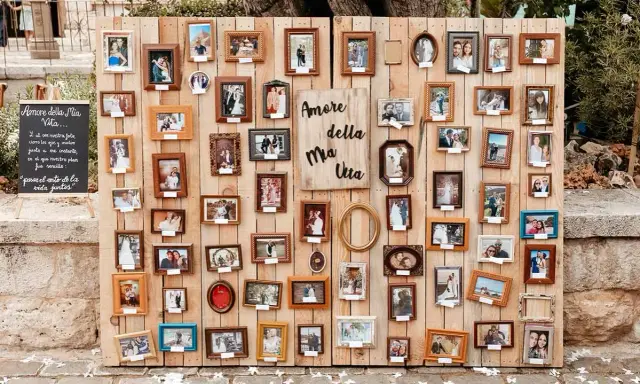 Un original seating plan boda con muchas fotos de parejas en marcos de madera.