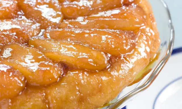 Une délicieuse tarte tatin aux pommes caramélisées, servie dans un plat en verre.