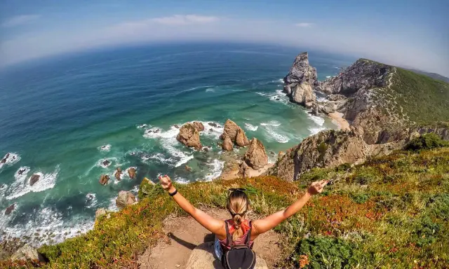 Frau genießt die atemberaubende Lissabon Natur am Cabo da Roca. Türkises Meer, Felsen und üppige Vegetation.