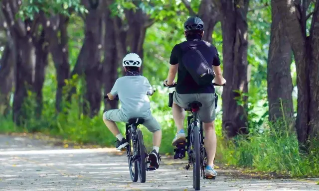 Dwie osoby na rowerach jadą alejką wśród drzew. Idealne miejsce na odkrywanie tras rowerowych Rzeszów.