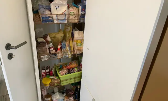Ein offener Apothekerschrank mit vielen Lebensmitteln. Hier wird gezeigt, wie man einen Apothekerschrank organisieren kann, um Platz zu sparen.