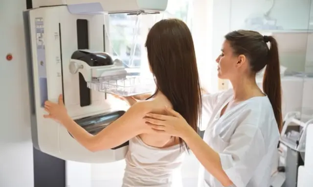 Badanie mammograficzne: co to jest? Pacjentka przygotowuje się do mammografii, a technik pomaga jej ustawić się przy aparacie.