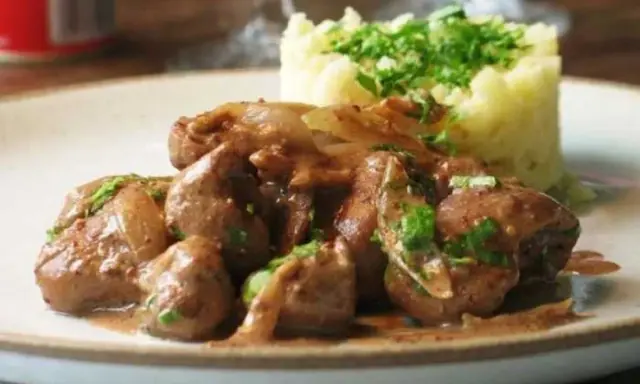 Une assiette de fricassée de rognons de veau, tendres et savoureux, accompagnés d'une purée de pommes de terre onctueuse et garnie de persil frais.
