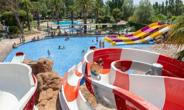 Disfruta de los mejores campings de Catalunya con piscinas y toboganes acuáticos. Familias se divierten en un día soleado.