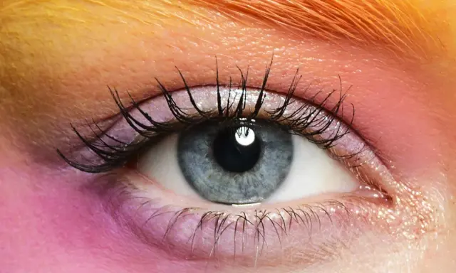 Occhio azzurro con ombretto rosa e arancione, ciglia lunghe e folte. Un esempio di come truccare gli occhi piccoli per farli sembrare più grandi.