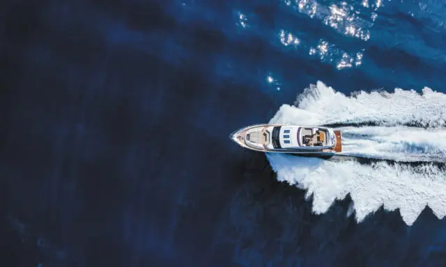 Un bateau hors-bord puissant fend les eaux bleues, laissant une traînée d'écume blanche derrière lui.